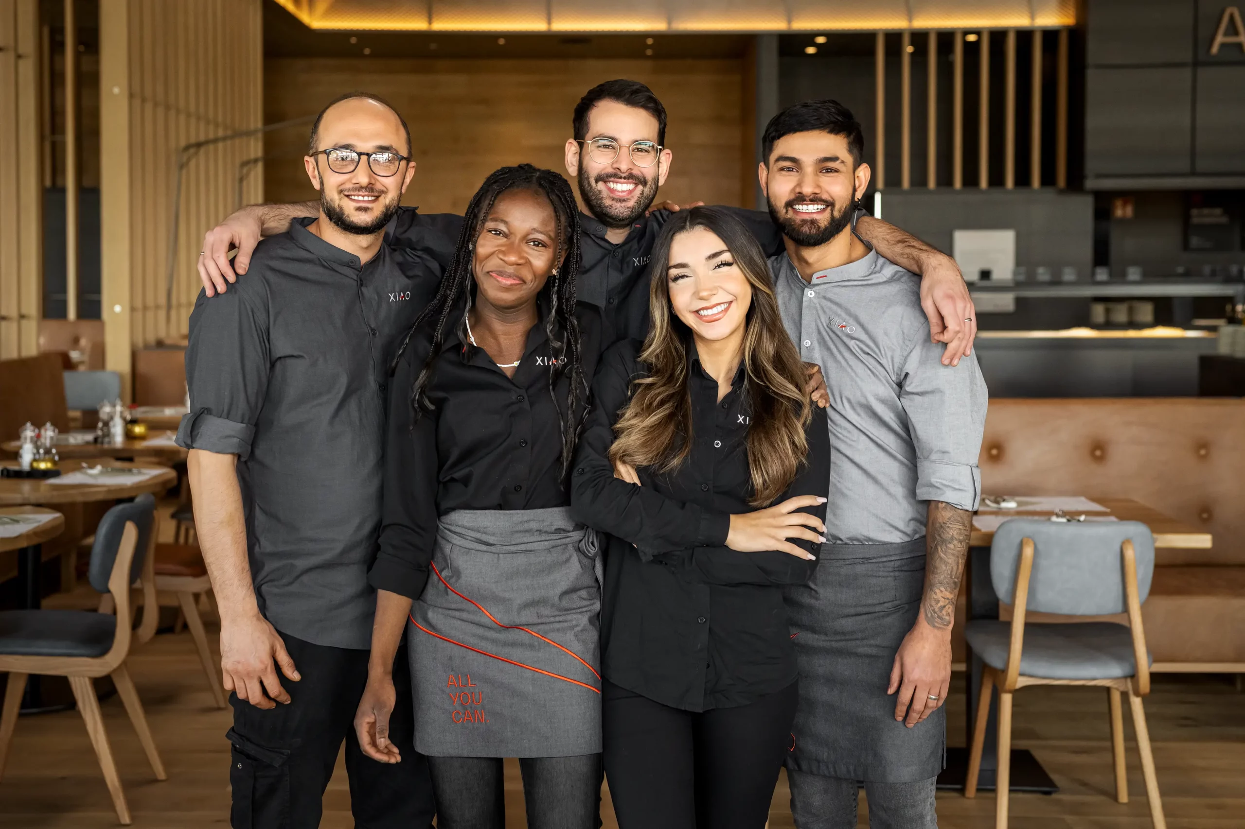 Eine Gruppe von fünf Buffet- Restaurant Servicekräften lächelt gut gelaunt in die Kamera
