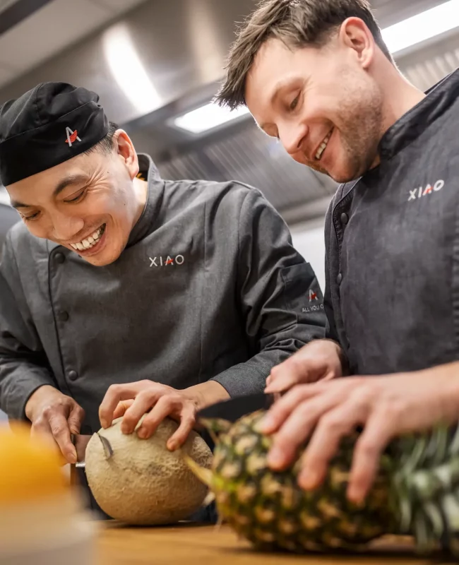 Zwei XIAO Mitarbeiter schneiden frisches Obst in der Gastro Küche